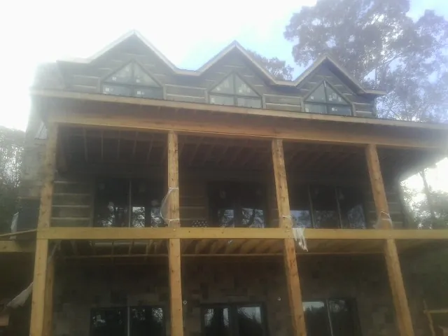 Dormers and porch framing on a large log home under construction — Roof Coating work by our crew in Sulphur Springs