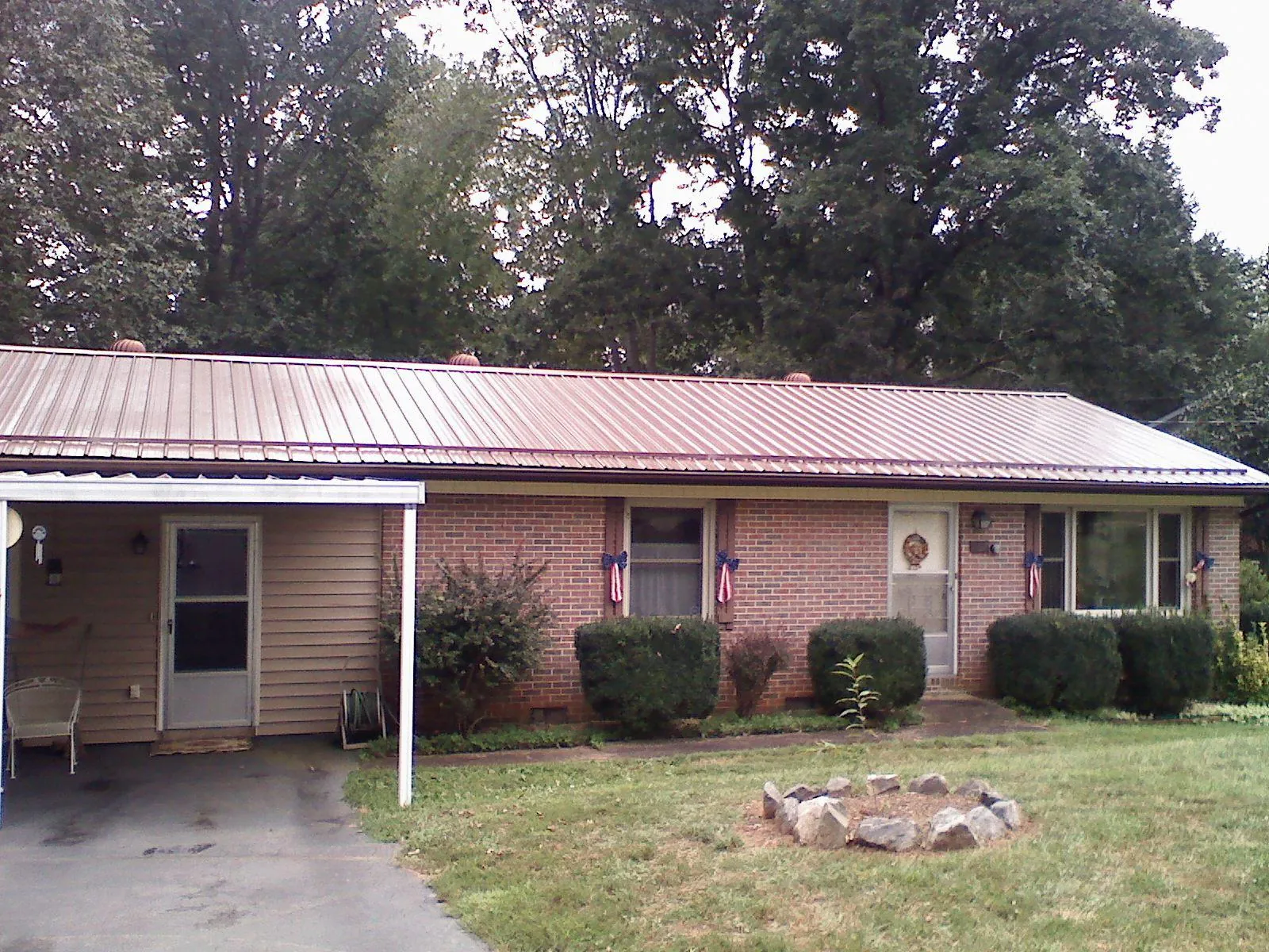 Bronze metal roof and carport on a brick ranch home — Roof Repair work by our crew in Sulphur Springs