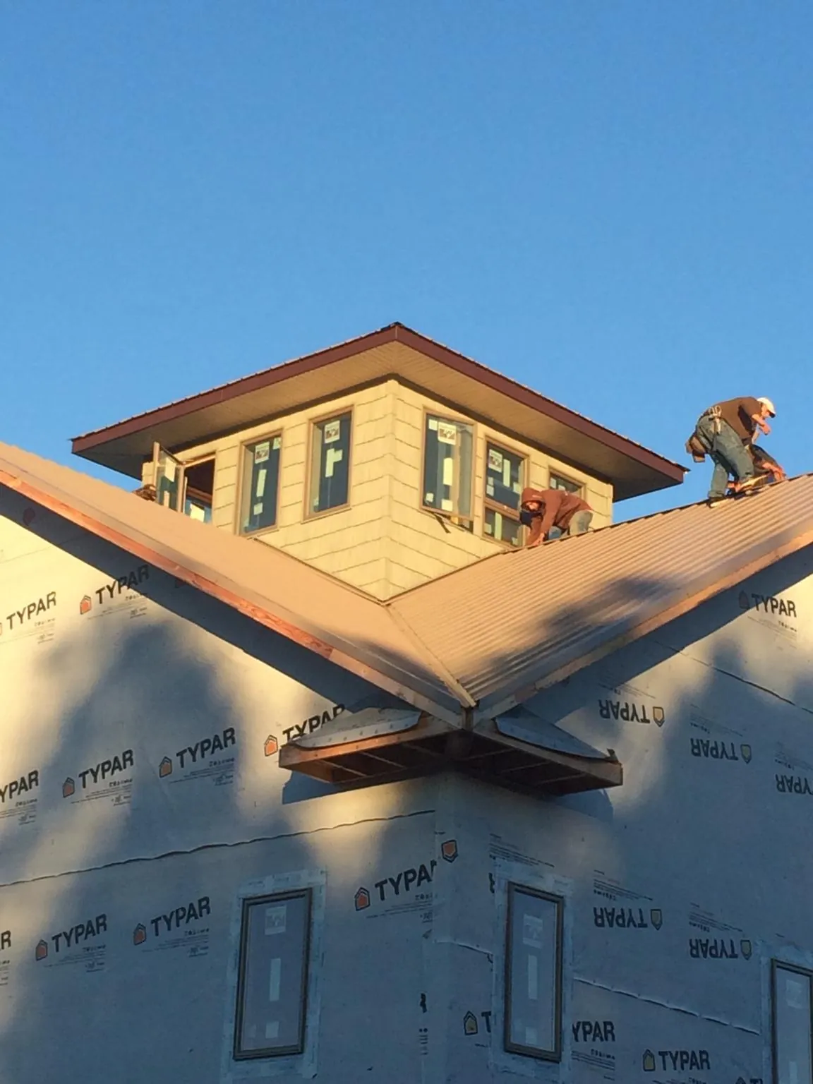 Roofers working around a rooftop cupola on a new metal roof at sunset — Roof Waterproofing in Sulphur Springs by Roofing Brothers